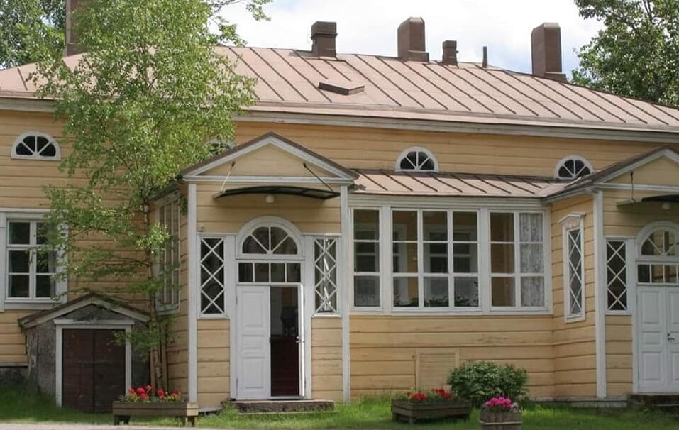 Keltainen 1800-luvun puinen kotiseututalo kesällä, ovi avoinna.